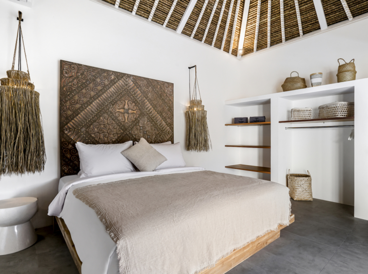 Double bed bedroom with Balinese handicrafts around at Cocotier Seminyak villa, walking distance to Seminyak beach Bali