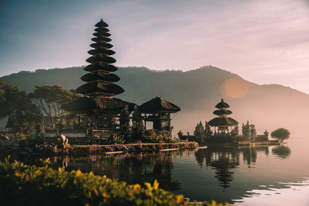 A Bali temple located next to a lake with mountains in the background