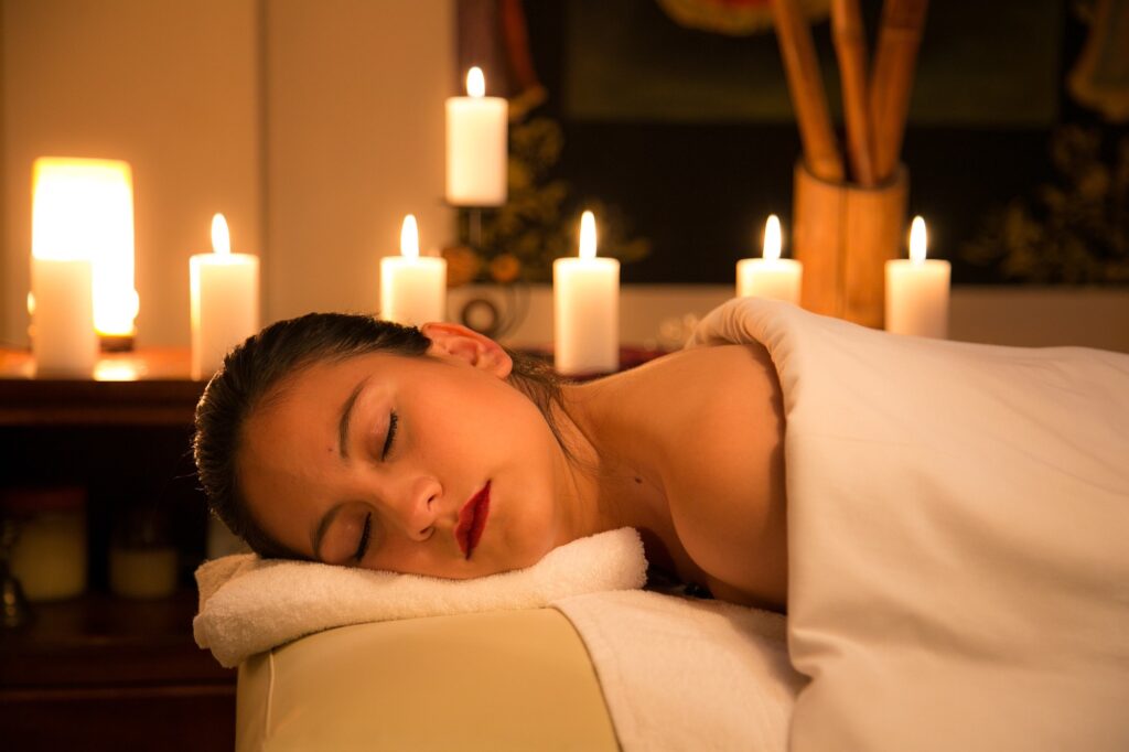 Woman laying on a massage table waiting for a Bali massage while being surrounded by candles